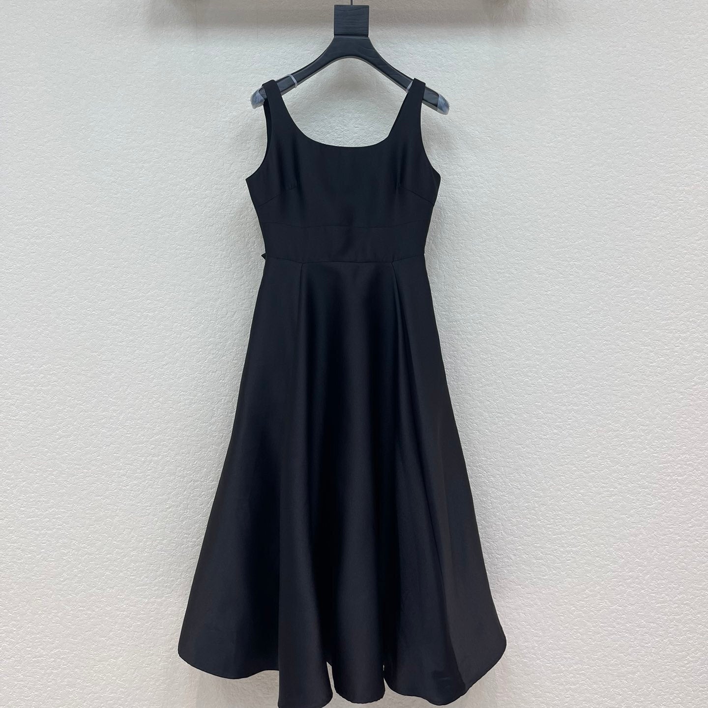 Black dress hanging on a rack against a white wall