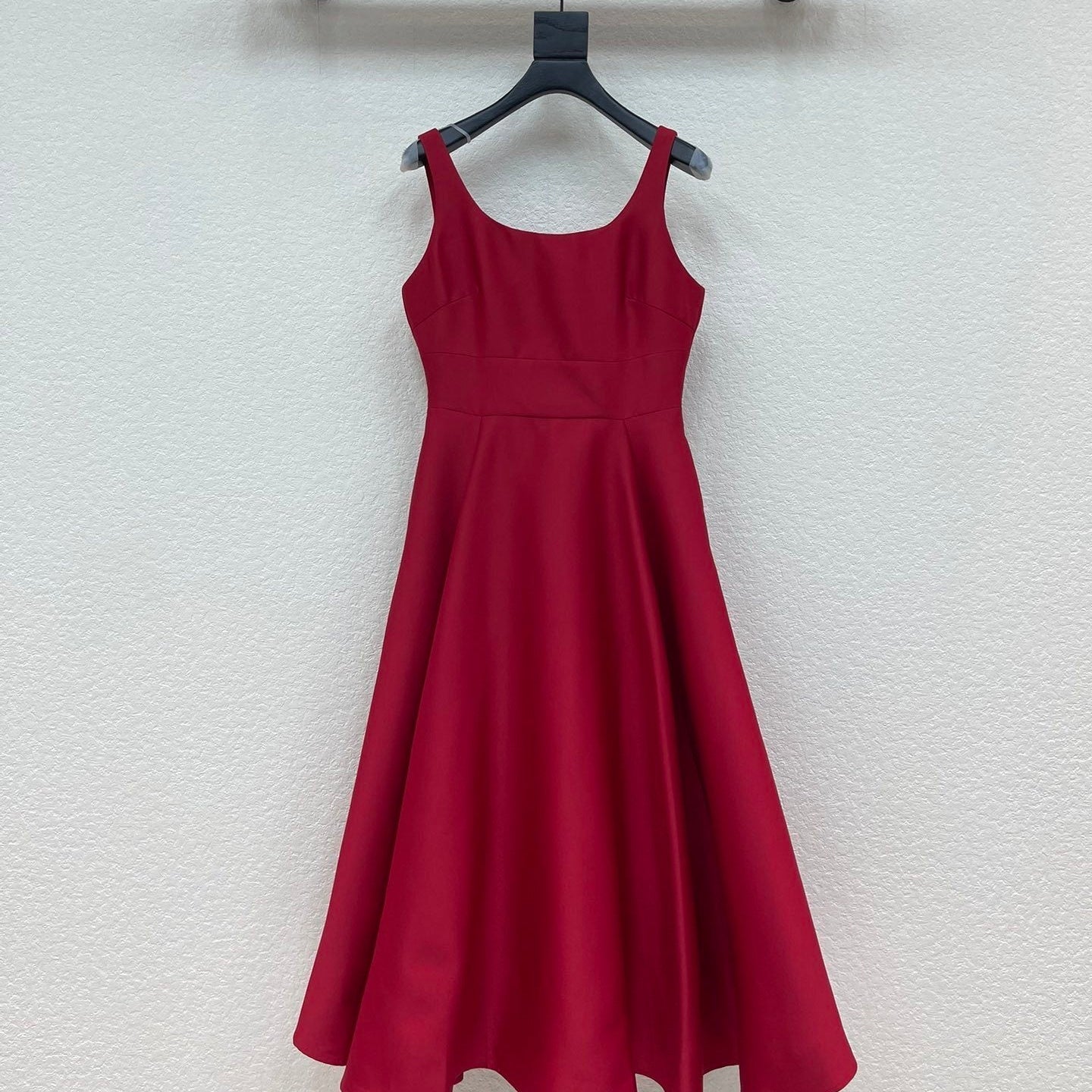 Red dress hanging on a black hanger against a white wall