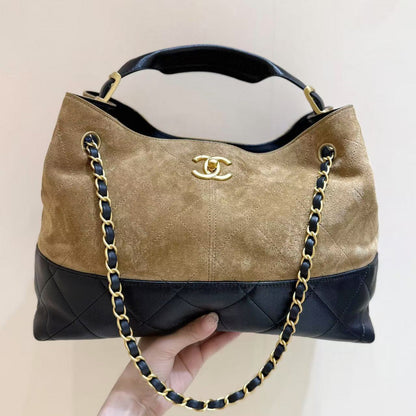 Chanel handbag with gold chain and logo on a beige background