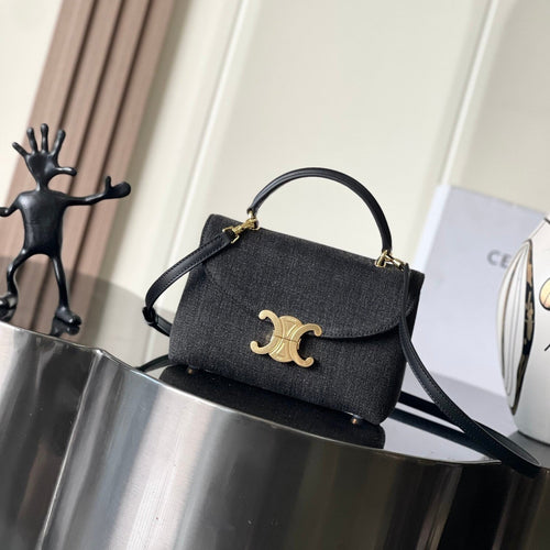 Black handbag with gold clasp on a metallic surface